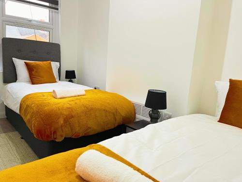 a bedroom with two beds with yellow and white sheets at Opal Apartment in Leicester