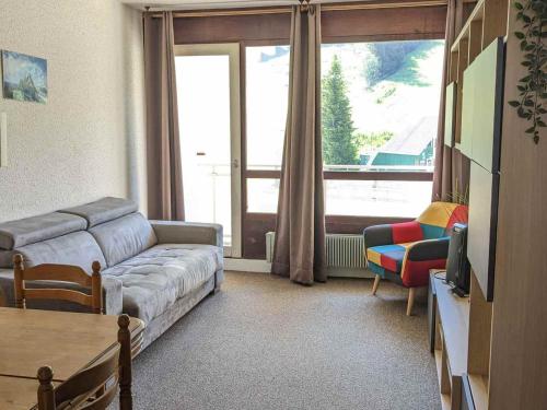 un salon avec un canapé et une grande fenêtre dans l'établissement Appartement 2 pièces au pied des pistes avec balcon et casier à skis - FR-1-557-101, à Les Adrets