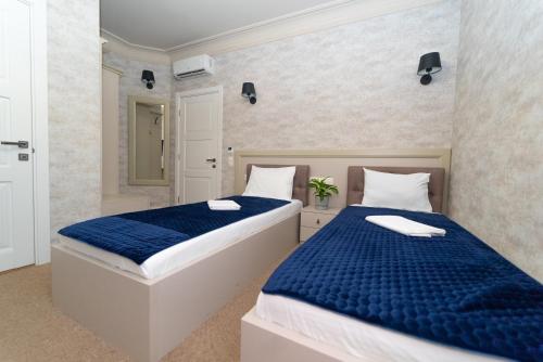 two beds in a room with blue sheets at Maner hotel in Odesa