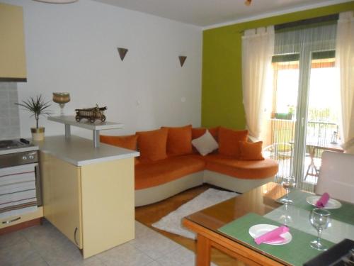 uma sala de estar com um sofá laranja na cozinha em Apartment Ivan em Trogir