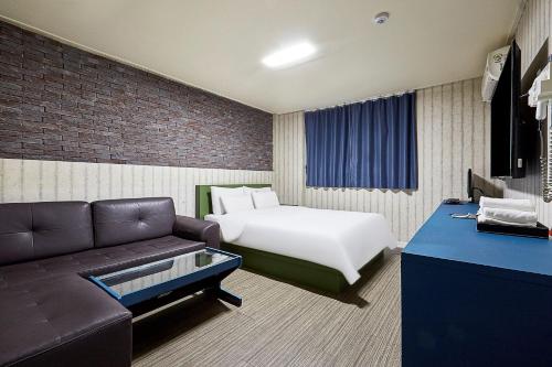 Habitación de hotel con cama y sofá en Galleria Hotel, en Suwon
