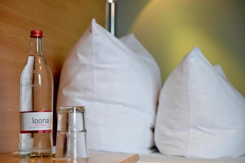 a bottle of wine sitting on a table with two pillows at Median Hotel Hannover Messe in Hannover