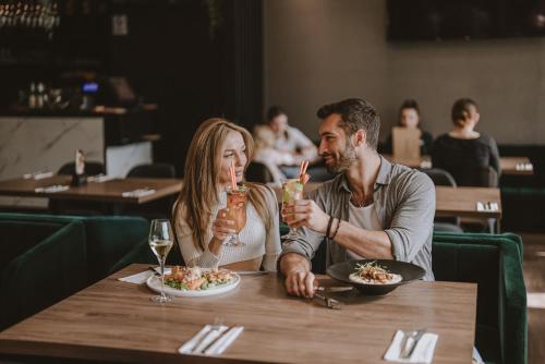 a man and woman sitting at a table eating food at Hotel Saltic Resort & Spa Grzybowo in Kołobrzeg
