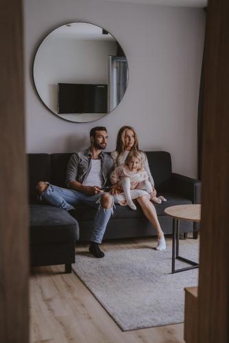 a man and woman sitting on a couch with a baby at Hotel Saltic Resort & Spa Grzybowo in Kołobrzeg