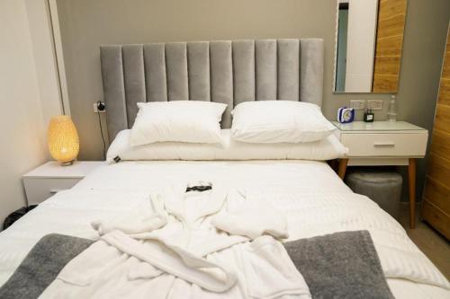 1 dormitorio con 1 cama con sábanas y almohadas blancas en Luxurious apartment for rent, en Kafr al ‘Ilw