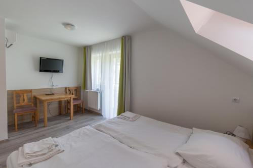 1 dormitorio con cama, mesa y TV en Diás Panzió, en Orfű
