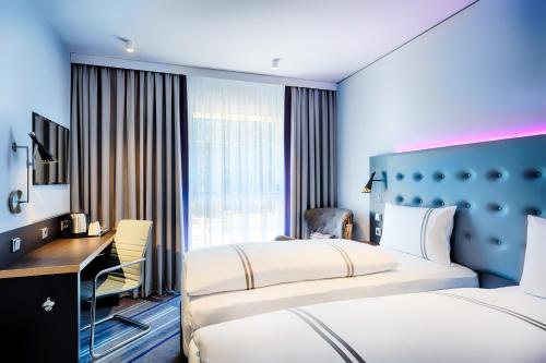 ein Hotelzimmer mit 2 Betten und einem Schreibtisch in der Unterkunft Premier Inn Saarbrücken City Centre in Saarbrücken
