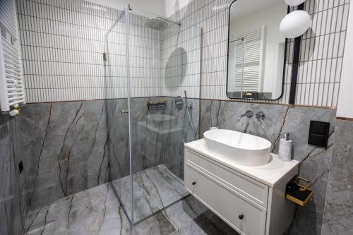 a bathroom with a shower and a sink and a mirror at Apartament Zoja II in Elblag
