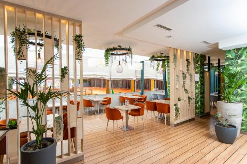 a restaurant with tables and chairs and plants at Hotel Bażantowo Sport in Katowice