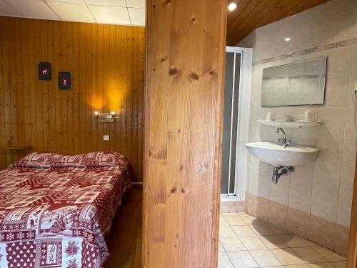 ein Bad mit einem Bett und einem Waschbecken. in der Unterkunft Hotel Les Granits in Combloux