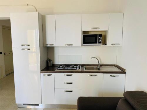 a kitchen with white cabinets and a microwave at Marasusa Apartments Maestrale 216C in Parghelia
