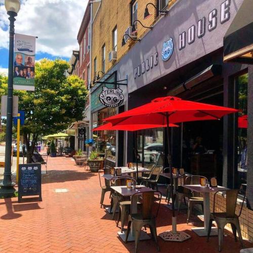 an outdoor cafe with tables and chairs with red umbrellas at 1255 Ashbridge, West Chester, PA in West Chester