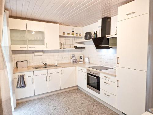 una cocina blanca con armarios blancos y fregadero en Ferienwohnung -Time to relax- bei Bamberg, mit herrlichem Blick auf das Maintal, en Viereth-Trunstadt