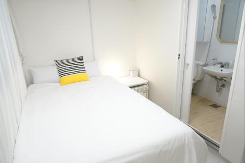 un letto bianco con un cuscino giallo in un bagno di Coco Stay a Seul