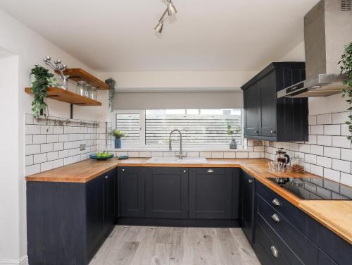 a kitchen with black cabinets and a sink at Dolwyn in Menai Bridge