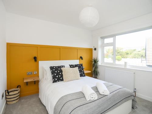 1 dormitorio con 1 cama grande y cabecero amarillo en Dolwyn, en Menai Bridge