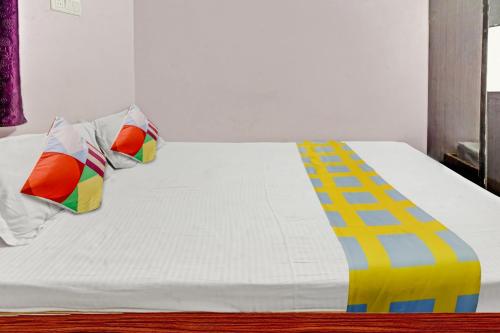 Super OYO Hotel Happy Inn في باتنا: سرير أبيض مع وسائد ملونة فوقه