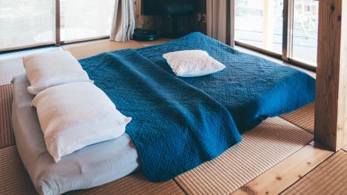 a bed with a blue blanket and two pillows on it at 田舎の静かな古民家の悠水居 in Itoman