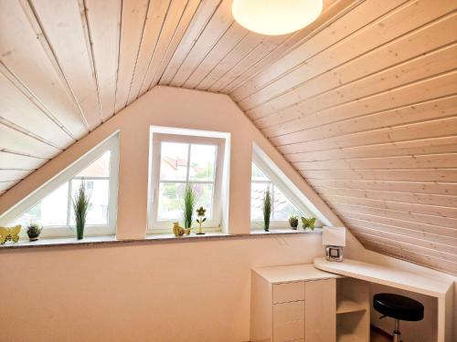 an attic room with a desk and windows at Ferienwohnung -Time to relax- bei Bamberg, mit herrlichem Blick auf das Maintal in Viereth-Trunstadt