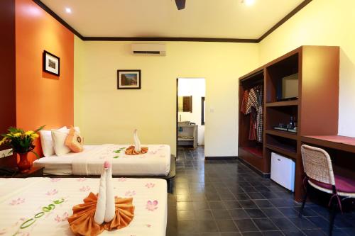 a hotel room with two beds and a television at Residence Indochine D'angkor in Siem Reap