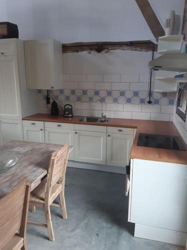 a kitchen with a table and chairs and a sink at appartement in authentiek koetshuis met bedstee in Moerstraten
