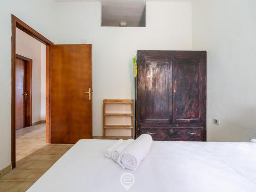 a bedroom with a white bed and a wooden door at Marine View House in Putzu Idu