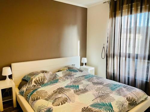 ein Schlafzimmer mit einem Bett mit einer Bettdecke mit Palmblättern in der Unterkunft Spacious Cozy Apartment close Paris & Flea Market at St Ouen in Saint-Ouen