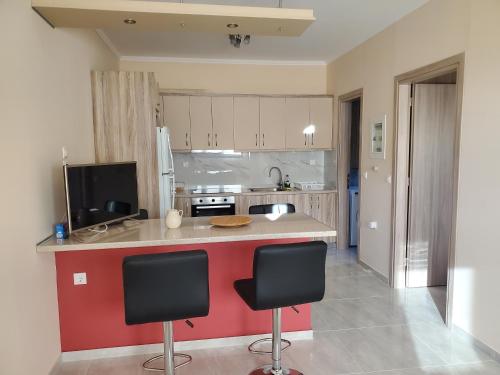 a kitchen with two bar stools and a red wall at Backyard Apartment in Lefkada Town