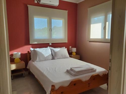 a bedroom with a bed with red walls and two windows at Backyard Apartment in Lefkada Town