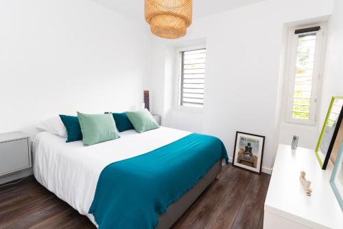 une chambre blanche avec un grand lit avec des oreillers bleus dans l'établissement Haut de Vauban, au pied de Notre Dame de la Garde - T3 Climatisé, à Marseille