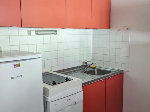 une petite cuisine avec des armoires rouges et un évier dans l'établissement Appartement 2 pièces au pied des pistes avec balcon et casier à skis - FR-1-557-101, à Les Adrets