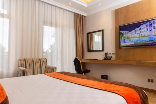 a hotel room with a bed and a flat screen tv at Alba Hotel Meru in Meru