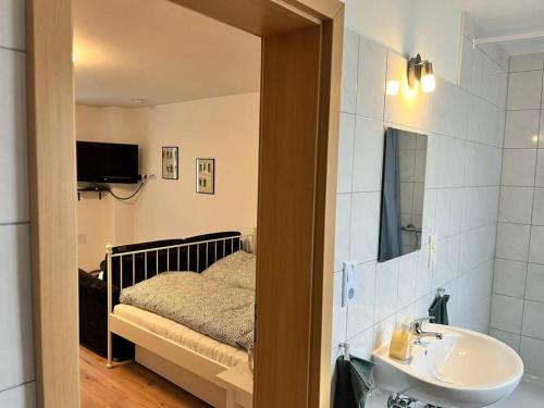 a bathroom with a bed and a sink and a mirror at Engelhard´s Ferien Apartment in Hillesheim