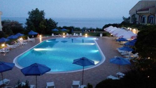 a large swimming pool with blue umbrellas and chairs at SUN AND FLOWERS APARTMENTS in front of the sea in Topola