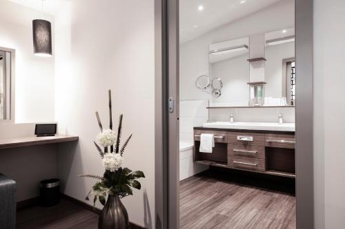 un bagno con lavandino e vaso con fiori di Nuhr Medical - Hotel & Restaurant a Senftenberg