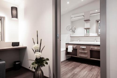 a bathroom with a sink and a vase with flowers at Nuhr Medical - Hotel & Restaurant in Senftenberg