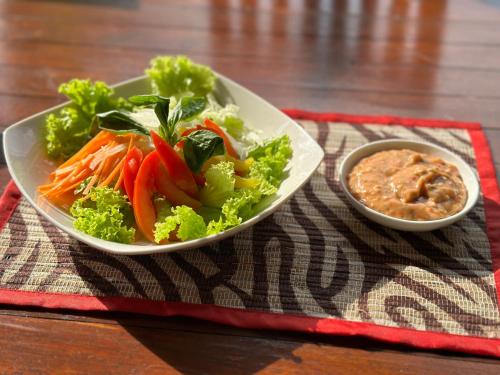 a plate of vegetables and a bowl of dip on a table at VILLA IPSA in Munduk