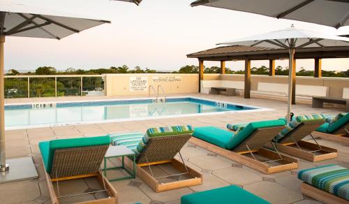 einen Pool mit Stühlen und einem Sonnenschirm in der Unterkunft Courtyard by Marriott Hilton Head Island in Hilton Head Island