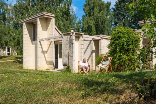 two people sitting in chairs in front of a house at Les Jardins de l'Anjou in La Pommeraye
