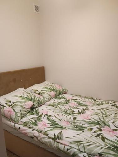 an unmade bed with pink flowers on it at Apartament Osiedle Bajkowe in Ostrów Wielkopolski