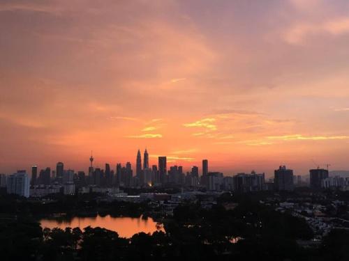 a city skyline with a sunset in the background at 3BR 8PAX KL City Centre KLCC View Ampang Boulevard Condo in Ampang
