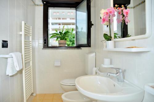 Un baño con lavabo, inodoro y espejo. en Hotel Etna, en Lignano Sabbiadoro