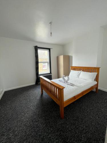 sypialnia z drewnianym łóżkiem w pokoju z oknem w obiekcie Lovely Guest House w mieście Kent