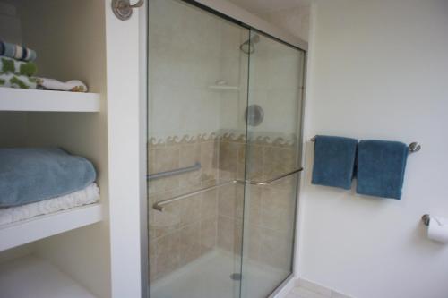 a glass shower in a bathroom with blue towels at Kona Pacific C319 in Kailua-Kona