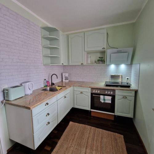a kitchen with white cabinets and a sink and a stove at Rema Ferienwohnungen in Zossen