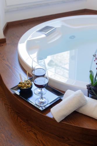 a tray with a glass of wine on a table next to a tub at Palazzo Ferrucci Luxury Suites in Cagliari