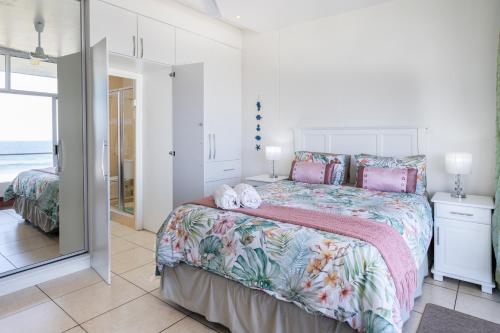 a bedroom with a large bed with pink and green sheets at Colonial Sands 403 in Margate