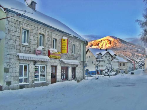 a building in the snow with a mountain in the background at Soba za goste Kraljica 3 in Kupres