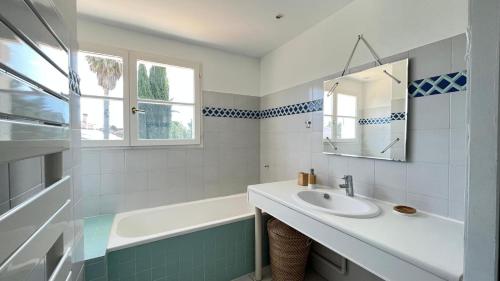 une salle de bain avec un lavabo, une baignoire et un miroir dans l'établissement Villa Piscine Golf Tennis Méditerranée, à Baillargues