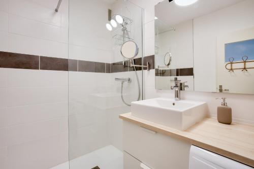 ein weißes Badezimmer mit einem Waschbecken und einem Spiegel in der Unterkunft Escapade sur l'île de Nantes avec vue sur la Loire in Nantes